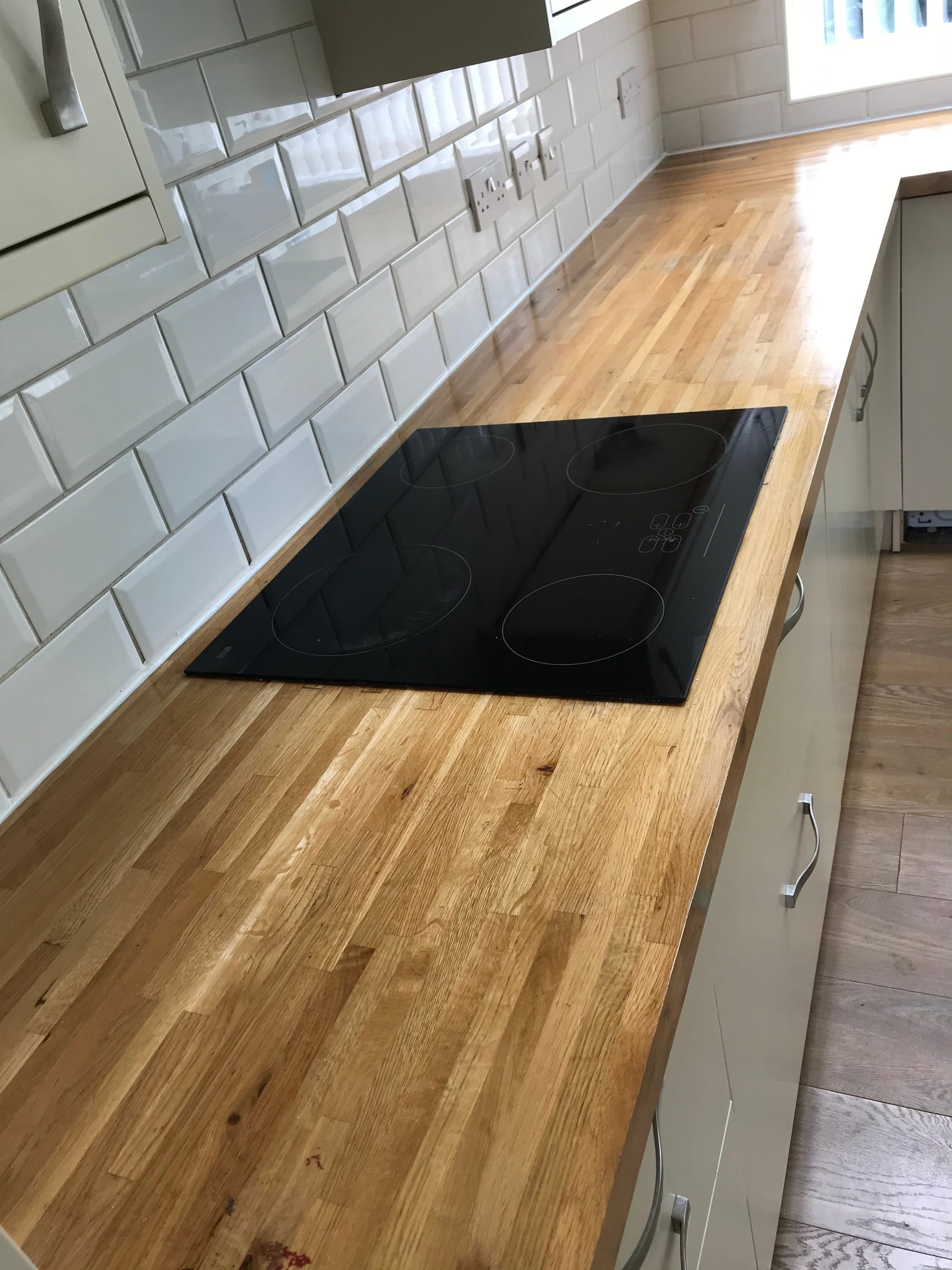 Timber kitchen worktop against white tiled walls