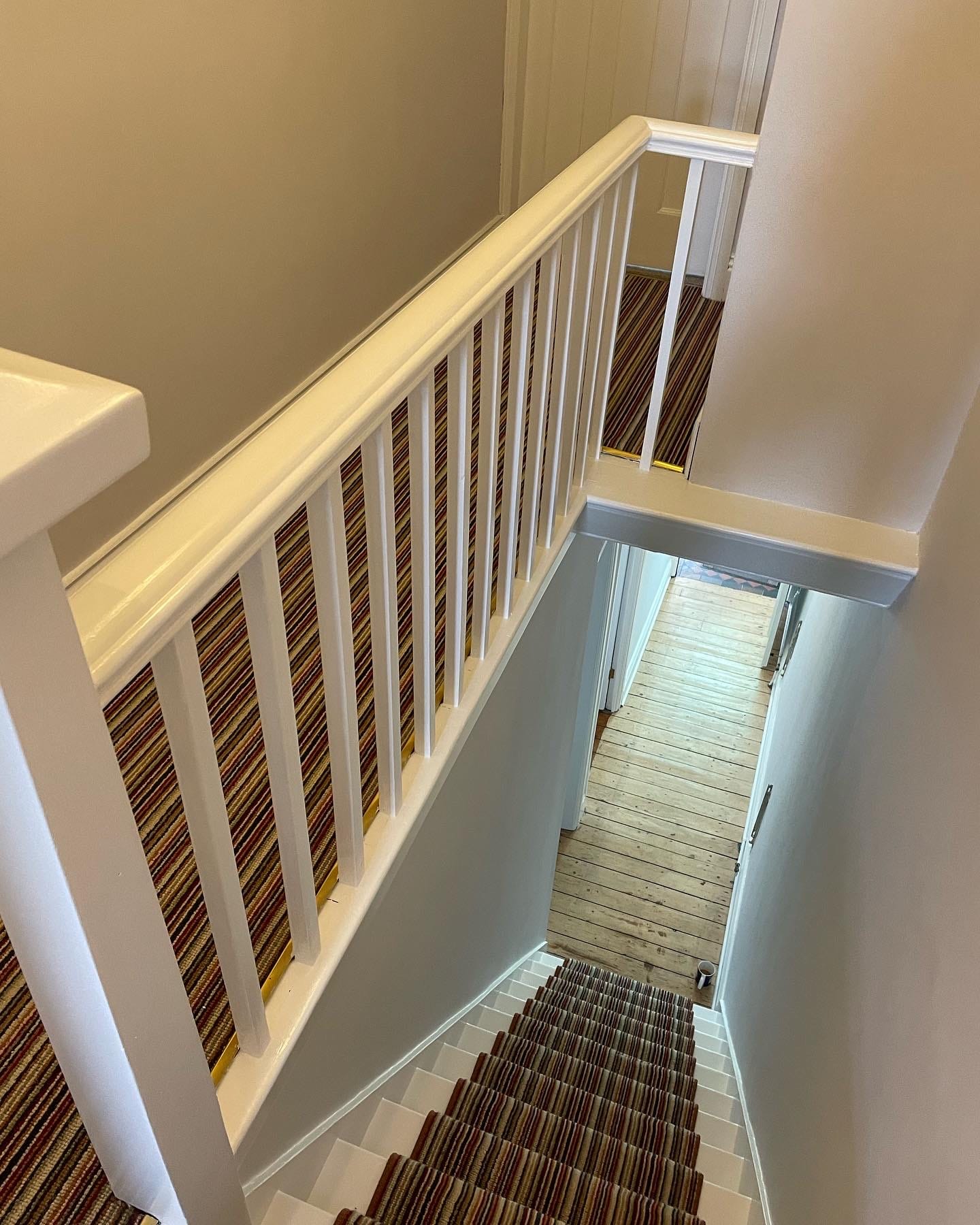 A decorated stairwell with white balustrades and warm neutral walls